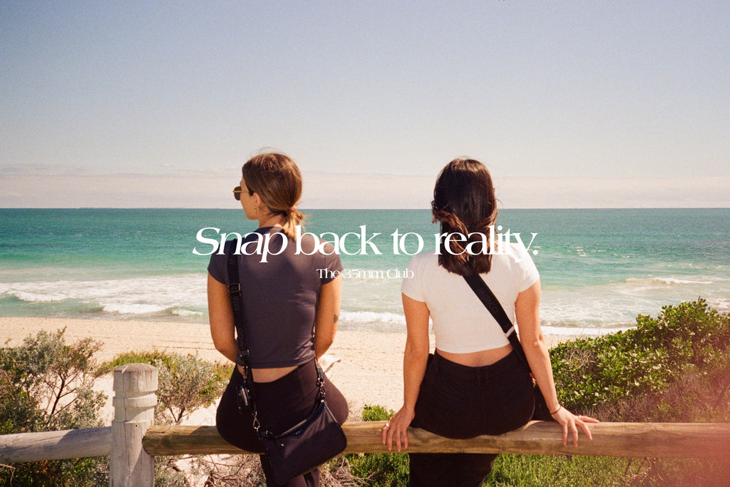 Our slogan 'Snap back to reality' over a photo of two girls sitting by the beach and watching the ocean