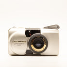 A photo of a vintage gold olympus 35mm point-and-shoot film camera