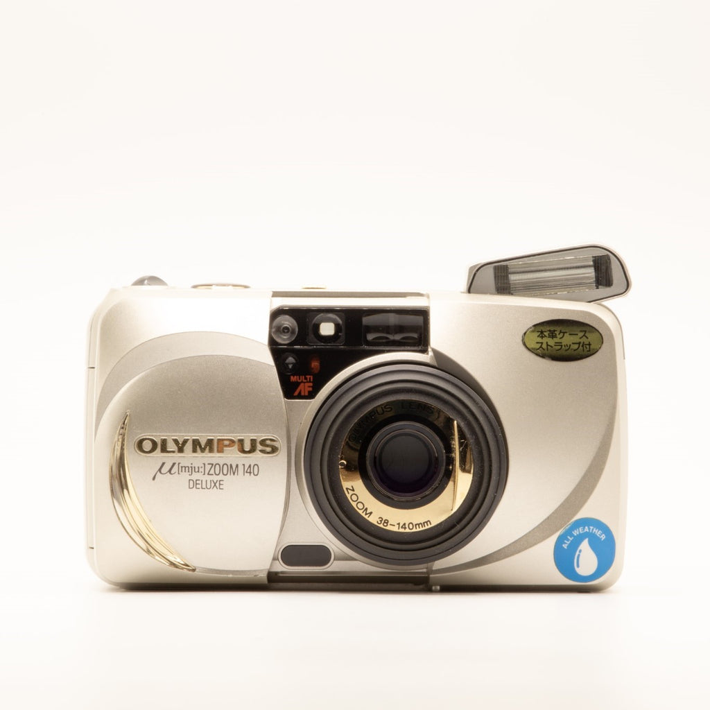 A photo of a vintage gold olympus 35mm point-and-shoot film camera