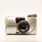 A photo of a vintage gold olympus 35mm point-and-shoot film camera