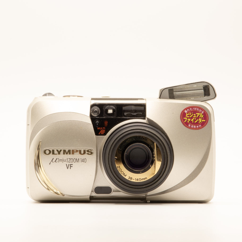 A photo of a vintage gold olympus 35mm point-and-shoot film camera