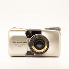 A photo of a vintage gold olympus 35mm point-and-shoot film camera